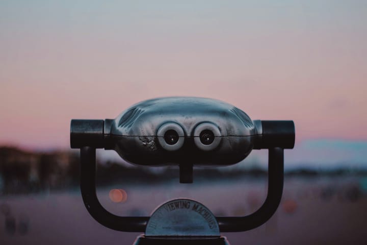 A coin-operated binocular viewer overlooking a vast landscape.